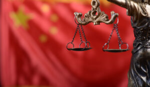 Scales of Justice, Justitia, Lady Justice in front of the flag of China in the background.